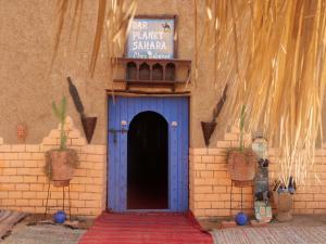 un edificio con una puerta azul y un cartel en él en hostels Planet Sahara, en Merzouga