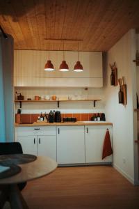 Aux Trois Chênes Lodge Spa في ميرْكو: مطبخ بدولاب بيضاء وسقف خشبي