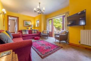 a living room with a red couch and a tv at Stable Cottage in Semer