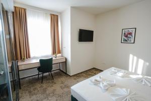 a hotel room with two beds and a desk at HOTEL NEST in Bijeljina