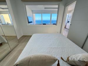 een slaapkamer met een groot bed en een groot raam bij ATICO VISTAS MAR PLAYA LAS CANTERAS in Las Palmas de Gran Canaria