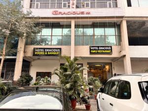 deux voitures garées devant un bâtiment dans l'établissement Hotel Gracious, à Gurgaon