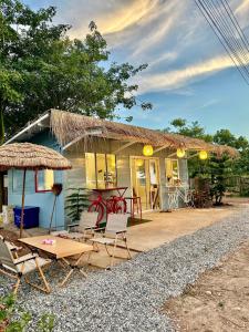 una casa con sillas, mesa y techo de paja en Peang Tara Cafe & Resort en Nong Khai