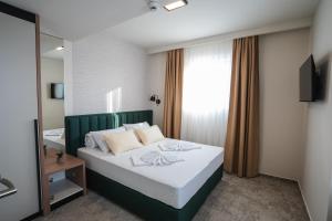 a bedroom with a bed with a green headboard and a mirror at HOTEL NEST in Bijeljina