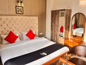 a bedroom with a bed with red pillows and a mirror at Hotel Gracious in Gurgaon