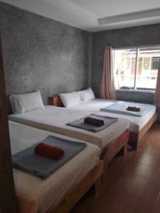 two twin beds in a room with a window at Charung Beach in Haad Rin