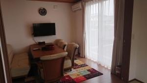 sala de estar con mesa, sillas y TV en 萩シーサイド堀内, en Hagi