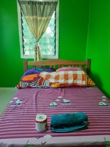 een bed met een paarse deken en een groene muur bij Ferafolia Highlands Home Stays in Auki