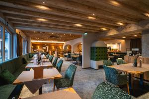 restauracja z drewnianymi stołami i krzesłami oraz restauracja ze stołami i krzesłami w obiekcie Hotel Hochfilzer w mieście Ellmau