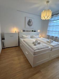 a white bedroom with two beds and a chandelier at Chiemgau Comfort A4 Ferienwohnanlage Oberaudorf mit Hallenbad und Sauna in Oberaudorf