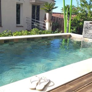 Un par de sandalias están sentadas en una piscina. en logement atypique avec jacuzzi et piscine, en Carnoules