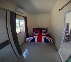 a bedroom with a bed with a red white and blue blanket at Pattaya pool villa in Ban Huai Yai