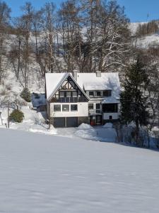 una casa está cubierta de nieve en la nieve en Ferienwohnung im Hambach, en Bad Berleburg