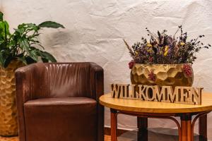 une chaise et une table avec un vase de fleurs dans l'établissement Hotel Hochfilzer, à Ellmau