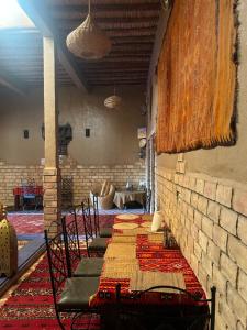 Habitación con mesa, sillas y pared de ladrillo. en kasbah Planet Sahara, en Merzouga