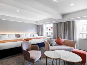 a hotel room with two beds and a couch at Daiwa Roynet Hotel Osaka-Kitahama in Osaka