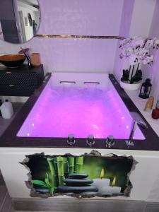 een hot tub in een badkamer met paarse verlichting bij Love Room romantique avec Jacuzzi 2 places in Perpignan