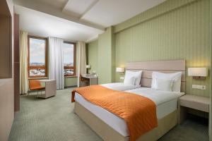 a bedroom with a large bed with an orange blanket at Hotel Golden Tulip Ana Tower Sibiu in Sibiu