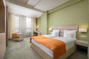 a hotel room with a bed with an orange blanket at Hotel Golden Tulip Ana Tower Sibiu in Sibiu