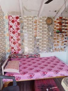 um quarto com uma cama rosa e uma parede de tijolos em Shri Raam Homestay Sirmoli Bhatronjkhan em Bhatrojkhan