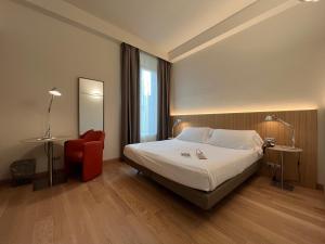 a hotel room with a bed and a red chair at Hotel Annunziata in Ferrara