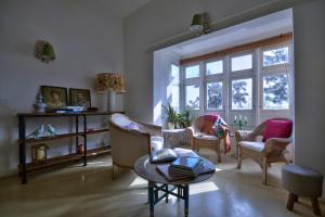 ein Wohnzimmer mit Stühlen, einem Tisch und Fenstern in der Unterkunft Vallettastay City break apartments in Valletta
