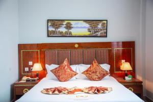 ein Schlafzimmer mit einem Bett mit zwei Kissen darauf in der Unterkunft Tiffany Diamond Hotels LTD - Makunganya in Daressalam