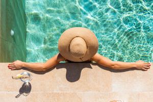 una mujer con sombrero sentada junto a una piscina en MEDANO4YOU Ixchel Beach House, en El Médano