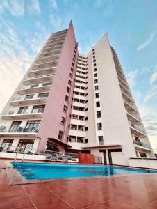 um edifício alto com uma piscina em frente em Luxury home 75”TV, 5mins from City Center & Beach em Dar es Salaam