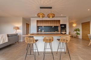 a kitchen with a counter and stools in a room at Villa du Menhir 300m plage à pied in Plouescat