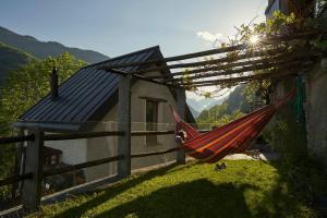 a red hammock hanging from a fence next to a house at Wild Valley Puro Ticino 1+2 in Valle Onsernone in Crana