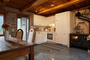a kitchen with white cabinets and a table and a fireplace at Wild Valley Puro Ticino 1+2 in Valle Onsernone in Crana
