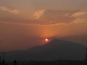 una puesta de sol sobre una montaña con el sol en el cielo en Family Home with Rooftop access and Mountain View, en Katmandú