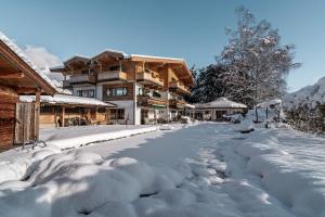 une route recouverte de neige devant une maison dans l'établissement Flora - Das kleine Gartenhotel, à Ellmau