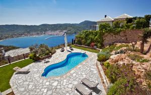 una piscina en un patio con sillas y una casa en Kohili Villas, en Skopelos Town