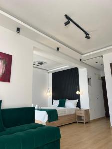 een slaapkamer met een bed en een groene bank bij Hotel NOBEL Ulcinj in Ulcinj