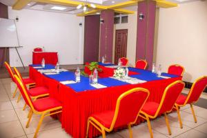 duży stół z czerwonymi krzesłami, niebieski stół i szezlong w obiekcie Hotel Wagon Wheel w mieście Nakuru