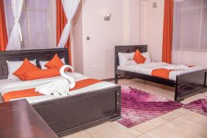 a bedroom with two beds with orange and white pillows at Hotel Wagon Wheel in Nakuru