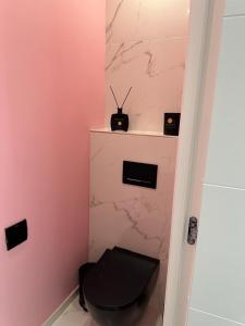 ein Bad mit einem schwarzen WC in einer rosa Wand in der Unterkunft non disponible in Champigny-sur-Marne