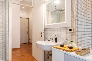 a white bathroom with a sink and a mirror at Mavi Flexyrent Apartment in Milan