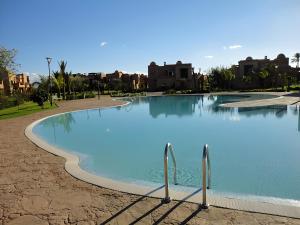 a large pool of blue water with buildings in the background at Atlas Views Appartements avec Piscine Golf de Marrakech in Marrakesh