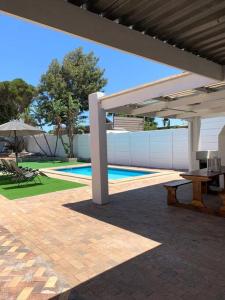 een patio met een tafel, een parasol en een zwembad bij Villa Lamsyh- your second home in Kaapstad
