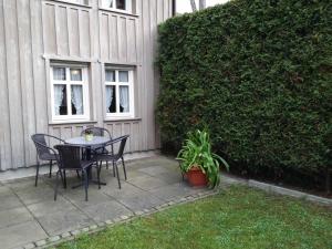 a patio with a table and chairs next to a hedge at Ferienwohnung im ältesten Fachwerkhaus in Blankenburg