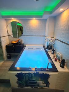 een groot bad in een badkamer met een groen licht bij Love Room romantique avec Jacuzzi 2 places in Perpignan