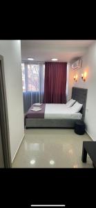 1 dormitorio con 1 cama grande y cortina roja en Hotel Fama, en Skopje