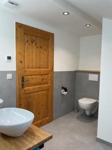 a bathroom with a wooden door and a toilet at NEU! FeWo Mansi in Chiemgau in Kienberg