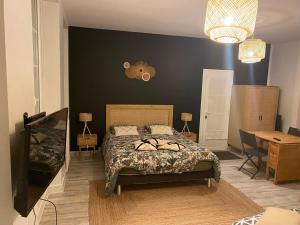 1 dormitorio con cama, mesa y escritorio en Les Cottages de la Norge, en Clénay