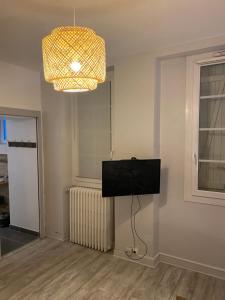 uma sala de estar com uma televisão e um lustre em Les Cottages de la Norge em Clénay
