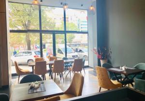un ristorante con tavoli e sedie e una grande finestra di Hotel Fama a Skopje
