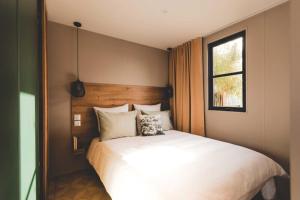Schlafzimmer mit einem großen weißen Bett und einem Fenster in der Unterkunft Verblijfpark Tulderheyde - Leisure only! in Poppel